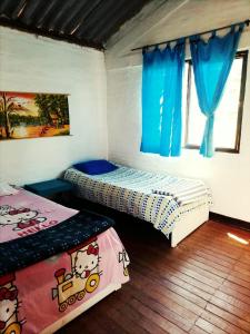 a bedroom with two beds and a window with blue curtains at alquilo en el queremal valle del cauca colombia in Papagalleros