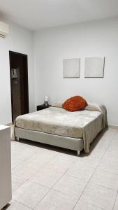 a bed with an orange pillow on it in a room at Casa de Huesped Sky Blue Barranquilla Colombia in Ciudad Jardín