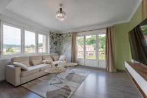 a living room with a couch and some windows at Le Marie 115m - Spacieux 3ch' - 2 sdb - Balcon in Joeuf