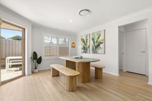 a living room with a table and two benches at Pipis Huskisson by Experience Jervis Bay in Huskisson