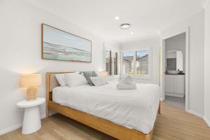a white bedroom with a bed and a window at Pipis Huskisson by Experience Jervis Bay in Huskisson
