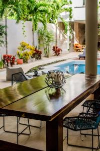 a large wooden table with chairs and a pool at Nomad Humans Coliving Apartments in Tulum