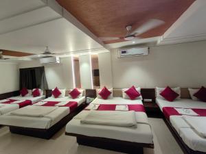 a row of beds in a room with red pillows at Hotel Anand Palace in Shirdi +212 photos