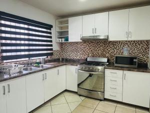 a kitchen with white cabinets and a stove and a microwave at Departamento en zona dorada de Tijuana in Tijuana +8 photos
