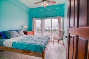 1 dormitorio con paredes azules, 1 cama y ventana en Suite C203 at Mara Laguna Gold Standard Certified, en San Pedro