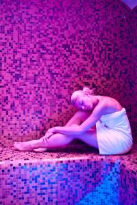 a woman sitting on the floor in a pink room at Hotel Garni Cristallo in Ponte di Legno
