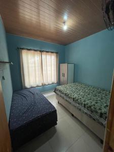 a bedroom with blue walls and a bed and a window at Casa com Piscina na Represa de Carlópolis in Carlópolis