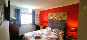 a bedroom with red walls and a bed and a window at Double room in riverside apartment in Glasgow