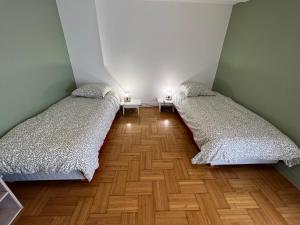 two beds in a small room with wooden floors at Spacieuse Maison de Village - Baby-foot & Fléchettes in Saint-Brisson-sur-Loire +3 photos