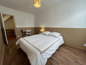 a bedroom with a large white bed and a table at Spacieuse Maison de Village - Baby-foot & Fléchettes in Saint-Brisson-sur-Loire
