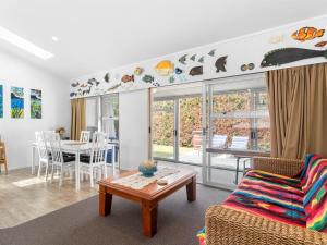 un soggiorno con un divano e un tavolo di Ruakaka Holiday Escape - Ruakaka Holiday Home a Ruakaka