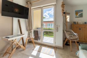 ein Wohnzimmer mit einem TV und einer Glasschiebetür in der Unterkunft Appartement pour 4 pers avec piscine tennis et parking 56 in Le Touquet-Paris-Plage