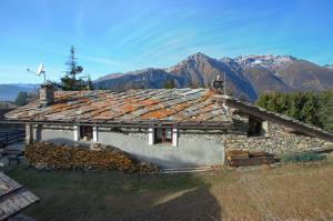 a stone house with a roof with mountains in the background at Chalet Clata Monfol Sauze in Monfol