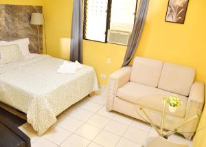 博卡奇卡Hotel Mango的一间卧室，里面有一张床、一张沙发和一把椅子