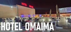 un gruppo di tavoli e sedie di fronte a un edificio di Hotel OMAIMA a Laayoune