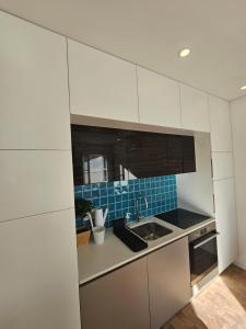 ポルトにあるRiver Blueの白いキャビネットとシンクのあるキッチン