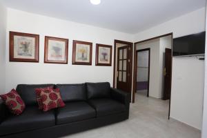 un salon avec un canapé noir et des tableaux au mur dans l'établissement Casa Pepi Sánchez Conil, à Conil de la Frontera