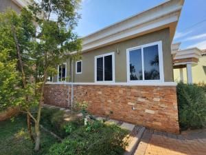 a home with a brick wall and trees at Tranquility Inn in Buzzi