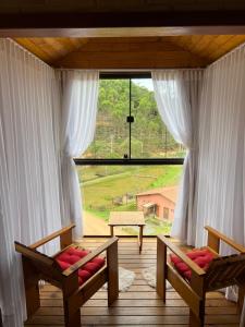 a room with two chairs and a large window at Chalés Villa Caravaggio in Santa Teresa