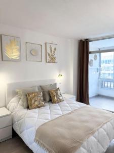 a white bed in a room with a window at Apartamento Playa Cañon del águila in Playa del Aguila