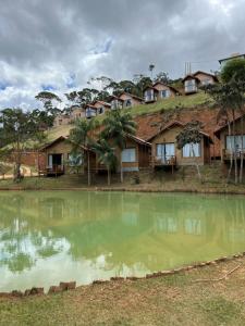 a group of houses with a pond in front at Chalés Villa Caravaggio in Santa Teresa