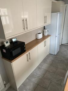 a kitchen with a counter with a microwave and a refrigerator at Apple blossom cottage contractor and holiday accommodation in Cleethorpes