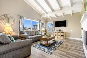 a living room with a couch and a tv at Stunning 2nd Floor Beachfront Home with Balcony, Ocean Views, and Prime Location in Newport Beach