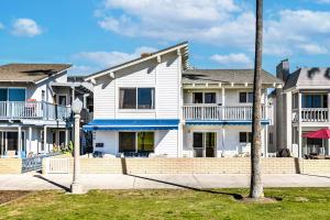 a row of white houses with a palm tree at Stunning 2nd Floor Beachfront Home with Balcony, Ocean Views, and Prime Location in Newport Beach