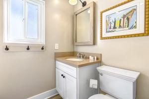a bathroom with a toilet and a sink and a mirror at Stunning 2nd Floor Beachfront Home with Balcony, Ocean Views, and Prime Location in Newport Beach +14 photos