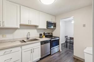 a kitchen with white cabinets and a sink and a stove at Scenic Towers 3020 I Cozy & Comfy I Free Parking in Parma