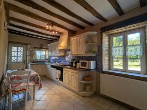 una cucina con armadi bianchi e un tavolo di Maison rénovée au cœur du Parc Naturel de la Brenne avec jardin et terrasse - FR-1-591-44 a Saint-Aigny