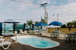 a swimming pool with chairs and tables and umbrellas at Pousada Canto da Vila in Saquarema