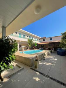 a swimming pool in a courtyard with a building at Suítes Brandi in Arraial do Cabo