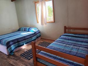 two beds in a room with a window at Hostal Al Yaras in Vicuña