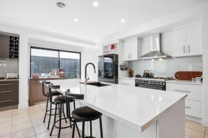 a kitchen with white cabinets and bar stools at Resort Living on Tempest in Torquay