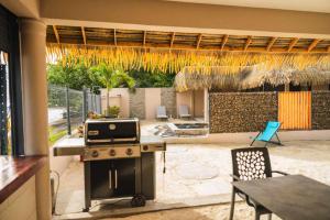 a kitchen with a grill and a patio with a table at Maison charmante bord de mer in Matiti
