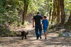 un hombre y un niño paseando a un perro por un sendero en Bungalows Verneda Mountain Resort en Arrós