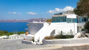 un bâtiment blanc sur le côté de l'eau dans l'établissement Villa Maria Rooms, à Akrotiri