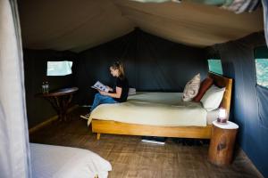 卡那封Wooramel River Retreat的坐在帐篷里的床上的女人