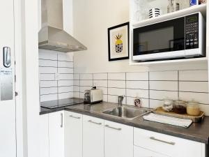 uma cozinha com pia e micro-ondas em Skytower views, washer & dryer, TV! em Auckland