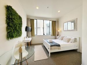 um quarto branco com uma cama e uma mesa de vidro em Skytower views, washer & dryer, TV! em Auckland