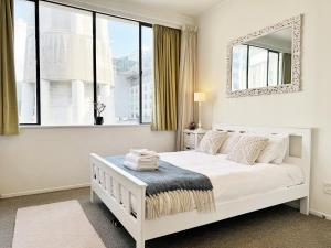 um quarto branco com uma cama e um espelho em Skytower views, washer & dryer, TV! em Auckland