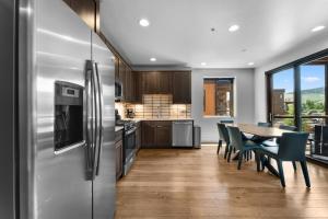 Una cocina con una mesa y un refrigerador de acero inoxidable. en Blue River Flats Bld 3 203 By Summit County Mountain Retreats, en Silverthorne