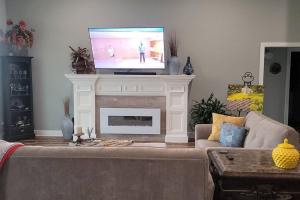 a living room with a tv on top of a fireplace at Waterfront Bama Getaway-20 min to UA in Englewood