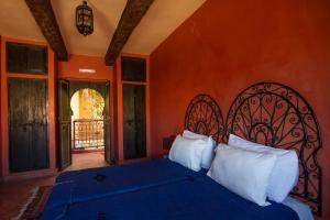 Schlafzimmer mit einem Bett mit blauer Bettwäsche und weißen Kissen in der Unterkunft Rose Noire in Ouarzazate