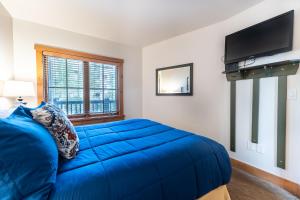 a bedroom with a blue bed and a flat screen tv at Expedition Station 8598 in Keystone