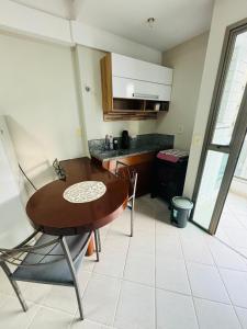 a kitchen with a wooden table and chairs in a room at Flat na orla Praia da Costa in Vila Velha