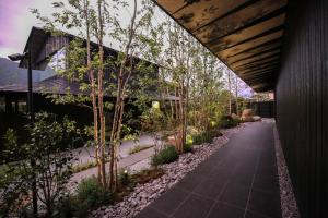a walkway in front of a building with trees at Comico Art House Yufuin in Yufuin