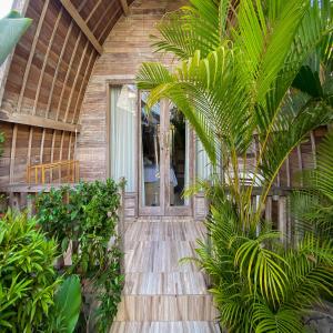 einen Holzweg, der zu einem Haus mit Palmen führt in der Unterkunft The Lumbung Residence in Kerobokan