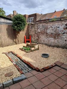 a garden with a red chair in front of a building at Maison rénovée 7P Proche de Lille in Tourcoing